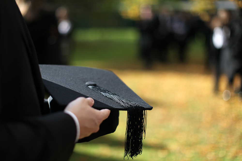 graduation hat held by a person offscreen